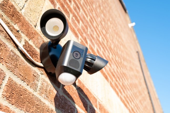 Newly installed, Wireless Internet CCTV camera system seen with PIR detector and two high power LED floodlights. Located on a side entrance to a house.