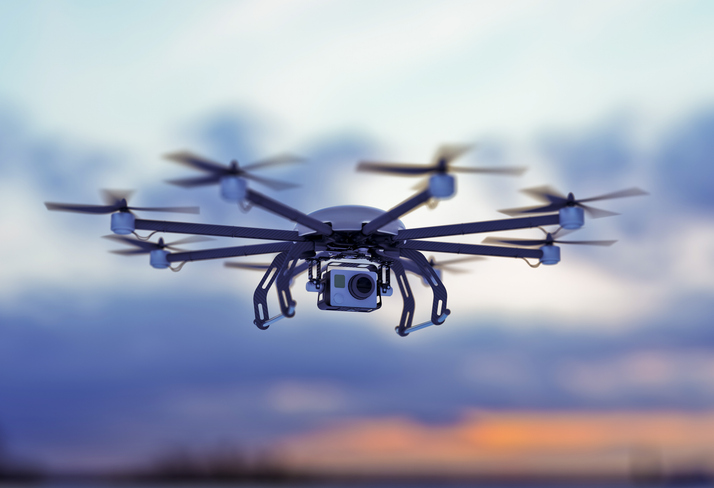 A drone flying in a cloudy sky where the sun goes down.