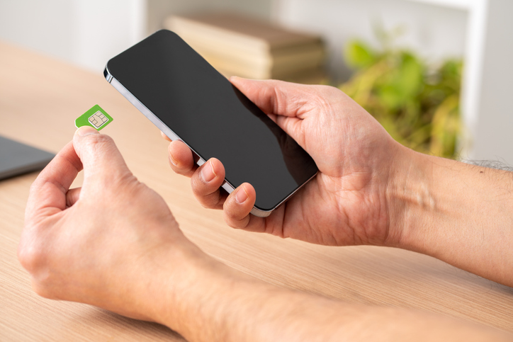 Close up of a man hands putting the sim card on the phone on a table.