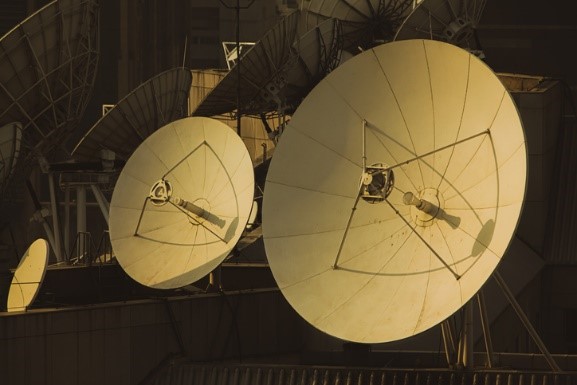 Two large front-facing satellite dishes with many other satellite dishes facing other directions in the background. 